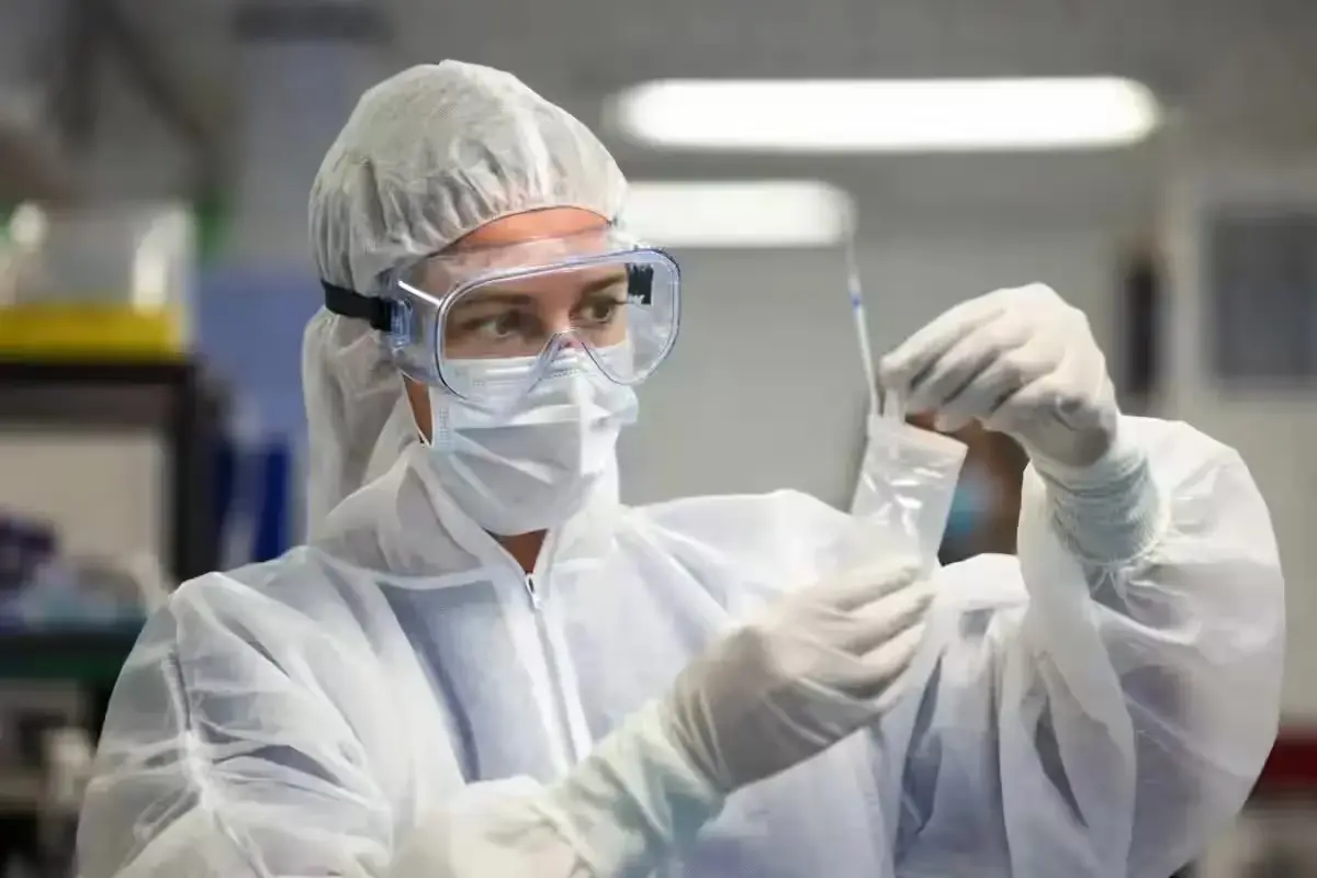 Health worker in PPE holding a biological sample for RT-PCR testing