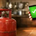 Red LPG gas cylinder in Indian kitchen with Aadhaar e-KYC verification screen on smartphone, March 2026