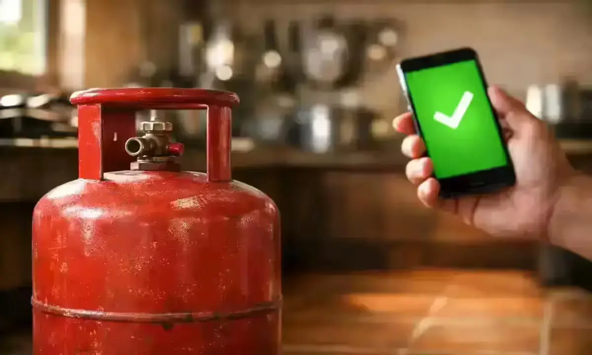 Red LPG gas cylinder in Indian kitchen with Aadhaar e-KYC verification screen on smartphone, March 2026