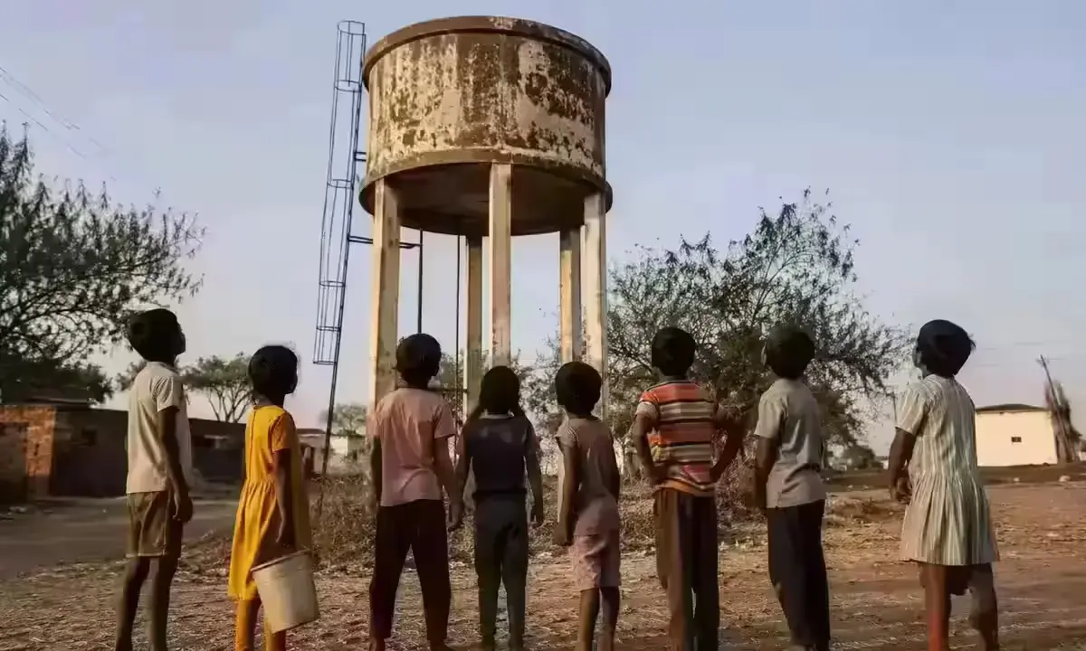 जल जीवन मिशन विफल - गाँव के बच्चे खाली पानी की टंकी के पास खड़े हैं